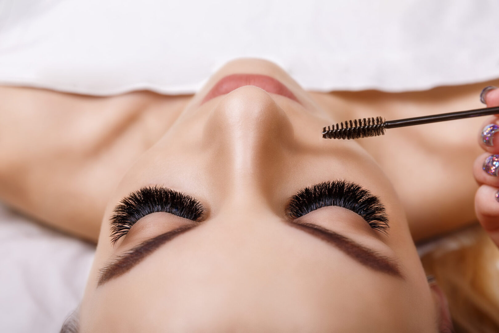 A woman with long eyelashes getting her brows trimmed.