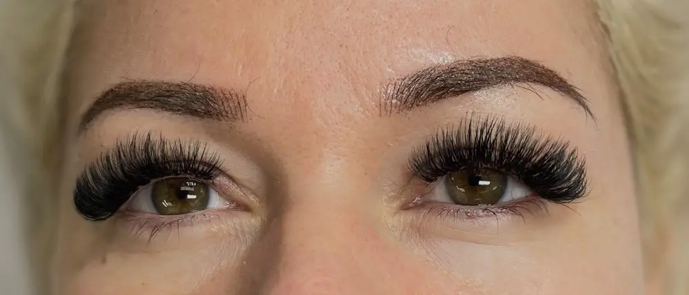 A woman with long eyelashes is looking at the camera.